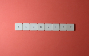 The image shows the word "Security" spelled out using white keyboard keys on a vibrant red background, suggesting the importance of security in digital environments.