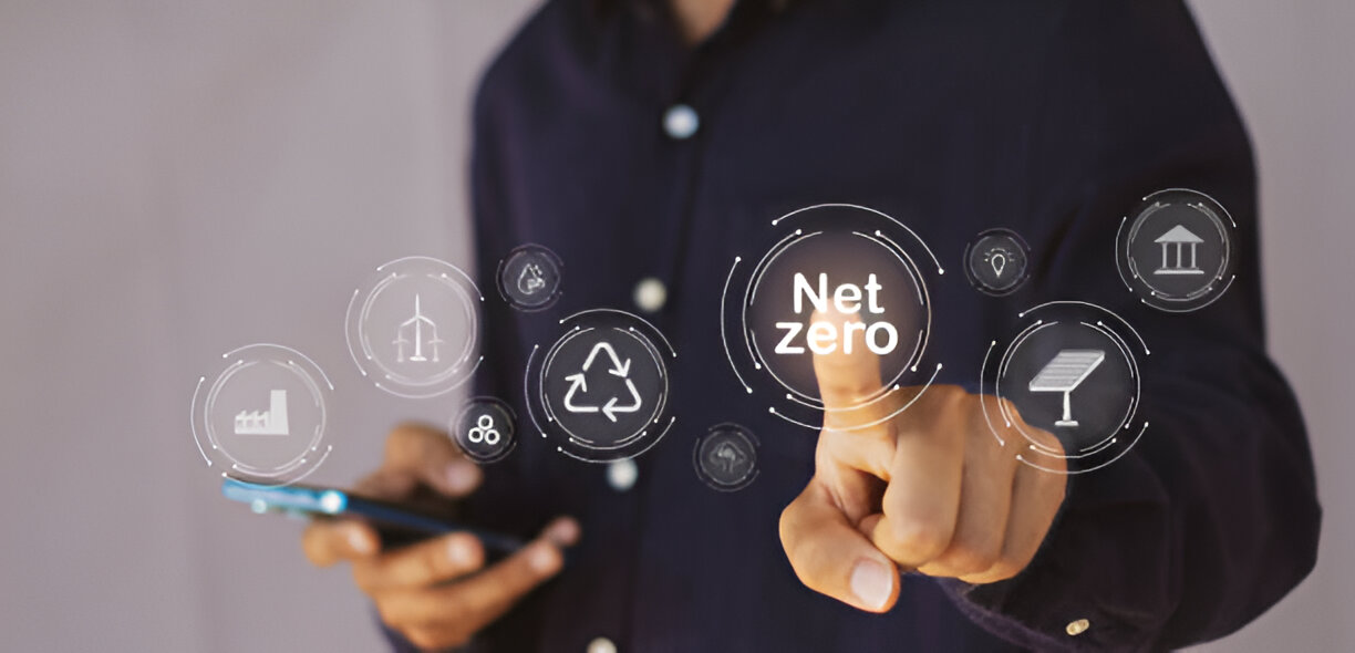 Digital interface showing 'Net Zero' concept with interconnected icons representing renewable energy, recycling, and sustainability, with a person touching the central 'Net Zero' button.
