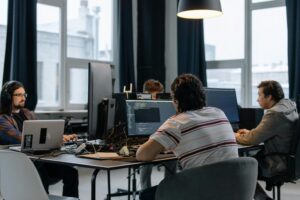 A group of tech professionals engaged in software engineering or web development, surrounded by the tools and equipment of their trade.