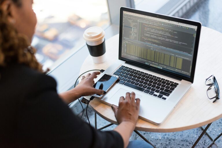Hands typing on a laptop keyboard, with a programming interface visible on the laptop screen.