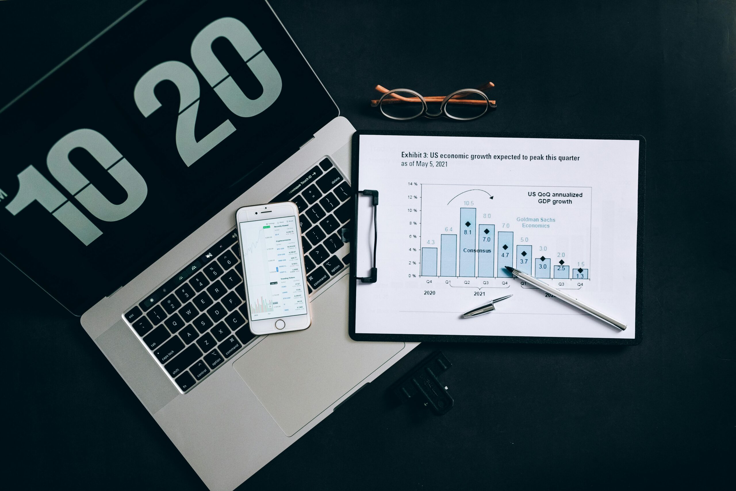 Data-Driven Decision Making: The image depicts a workspace equipped with the necessary technological and informational tools to support data-driven decision-making processes, such as evaluating economic trends and projections.
