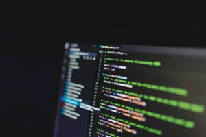 Laptop screen showing a code editor interface with lines of code, comments, and syntax coloring, representing a programming task or project.
