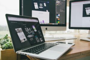 A desk setup with various digital devices, including an open laptop showcasing a software interface, denoting a technology-driven work environment.