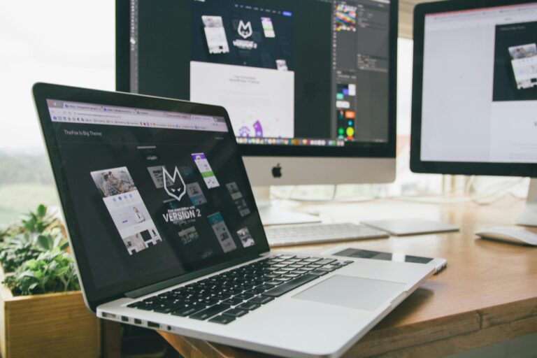 A desk setup with various digital devices, including an open laptop showcasing a software interface, denoting a technology-driven work environment.