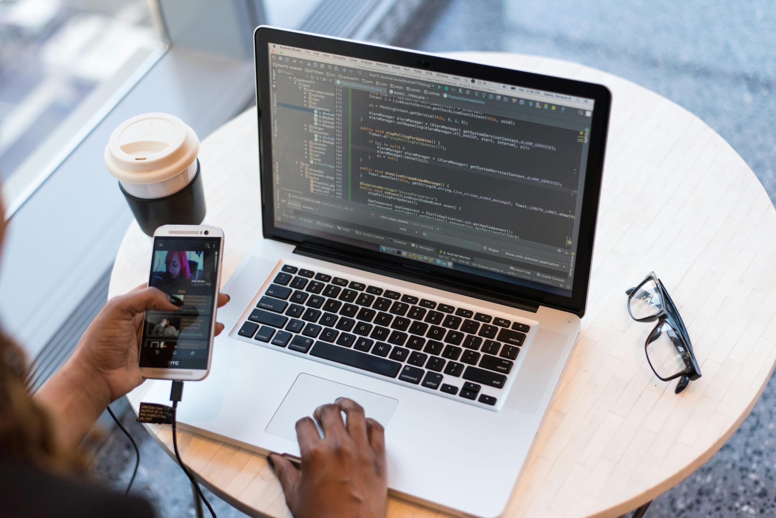 Desk setup with a laptop, smartphone, and coffee cup, highlighting the tools and environment of a software developer or programmer at work.