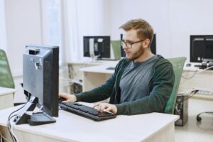 A professional-looking person engaged in computer-based work in a modern workspace.