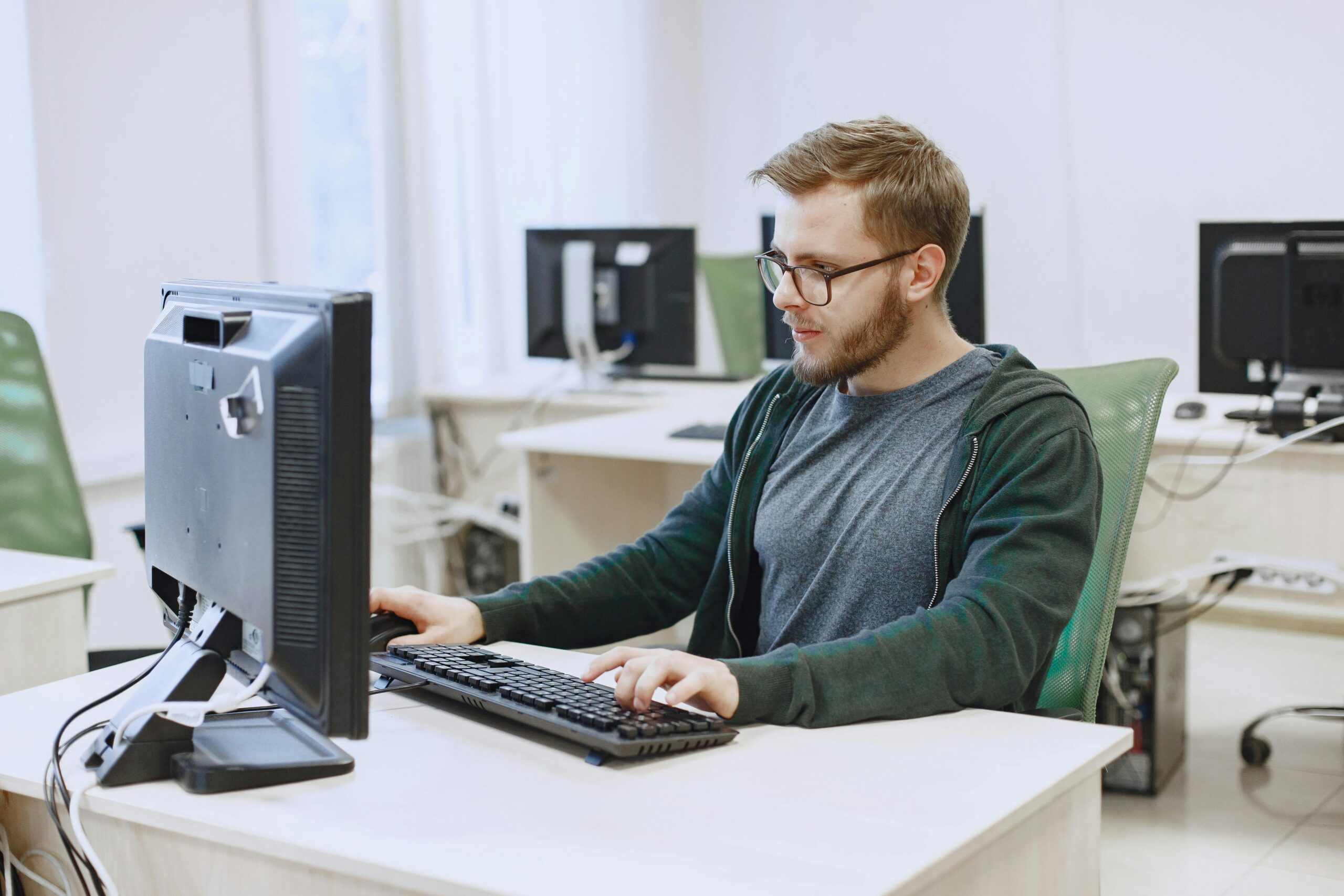 A professional-looking person engaged in computer-based work in a modern workspace.