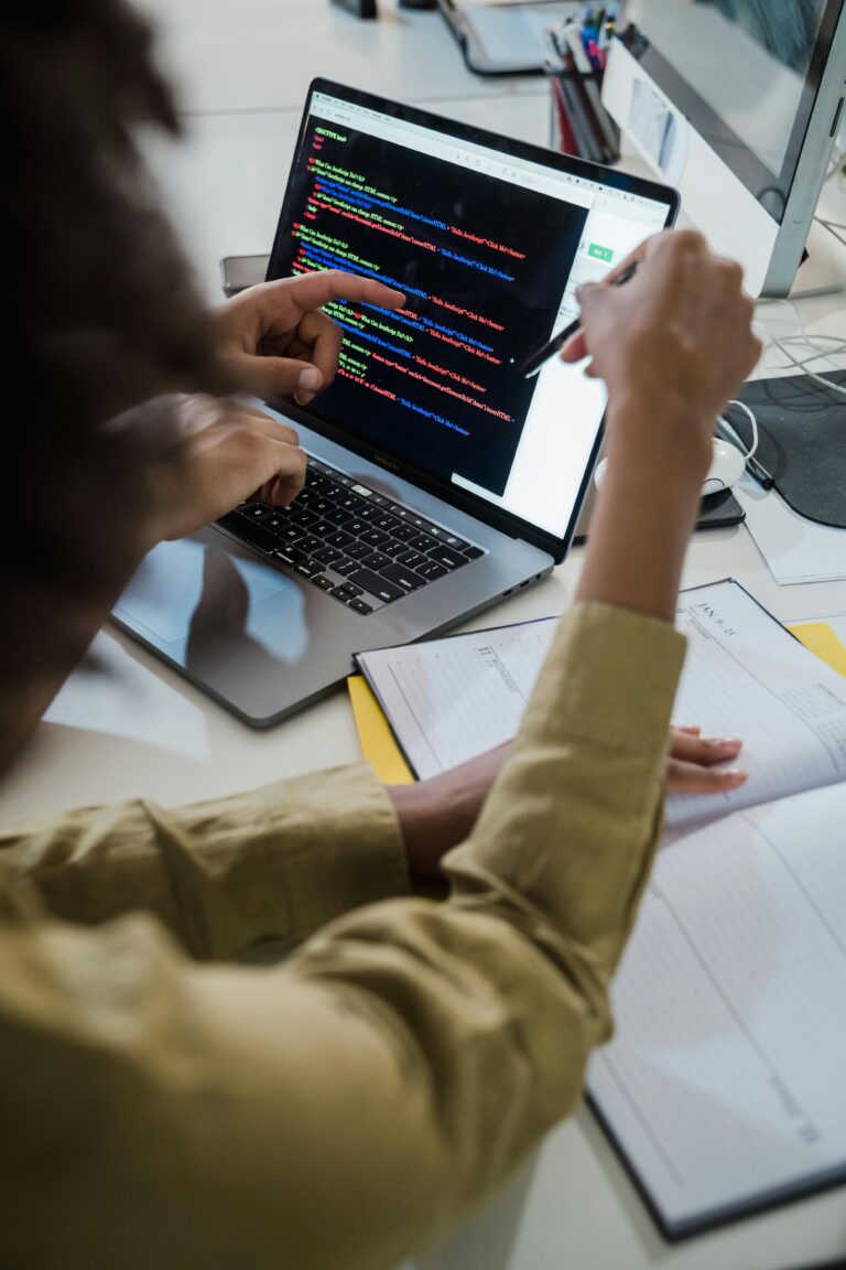 Hands of a programmer working on a coding project, focusing intently on the computer screen displaying software development code.