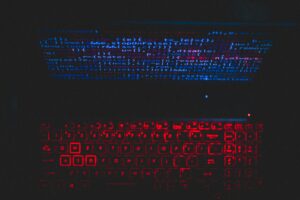 Futuristic-looking keyboard with vibrant blue and red lighting, surrounded by a dark background.