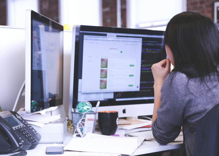 An individual immersed in coding or web development, their focus entirely on the computer screens in front of them.