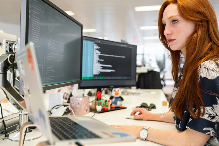 Female software developer intently working on coding and programming tasks in an office environment.