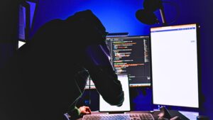 A person in a hoodie is seen at a computer, highlighting the importance of detecting credential theft attempts. Credit: unsplash.com (photo by Boitumelo)