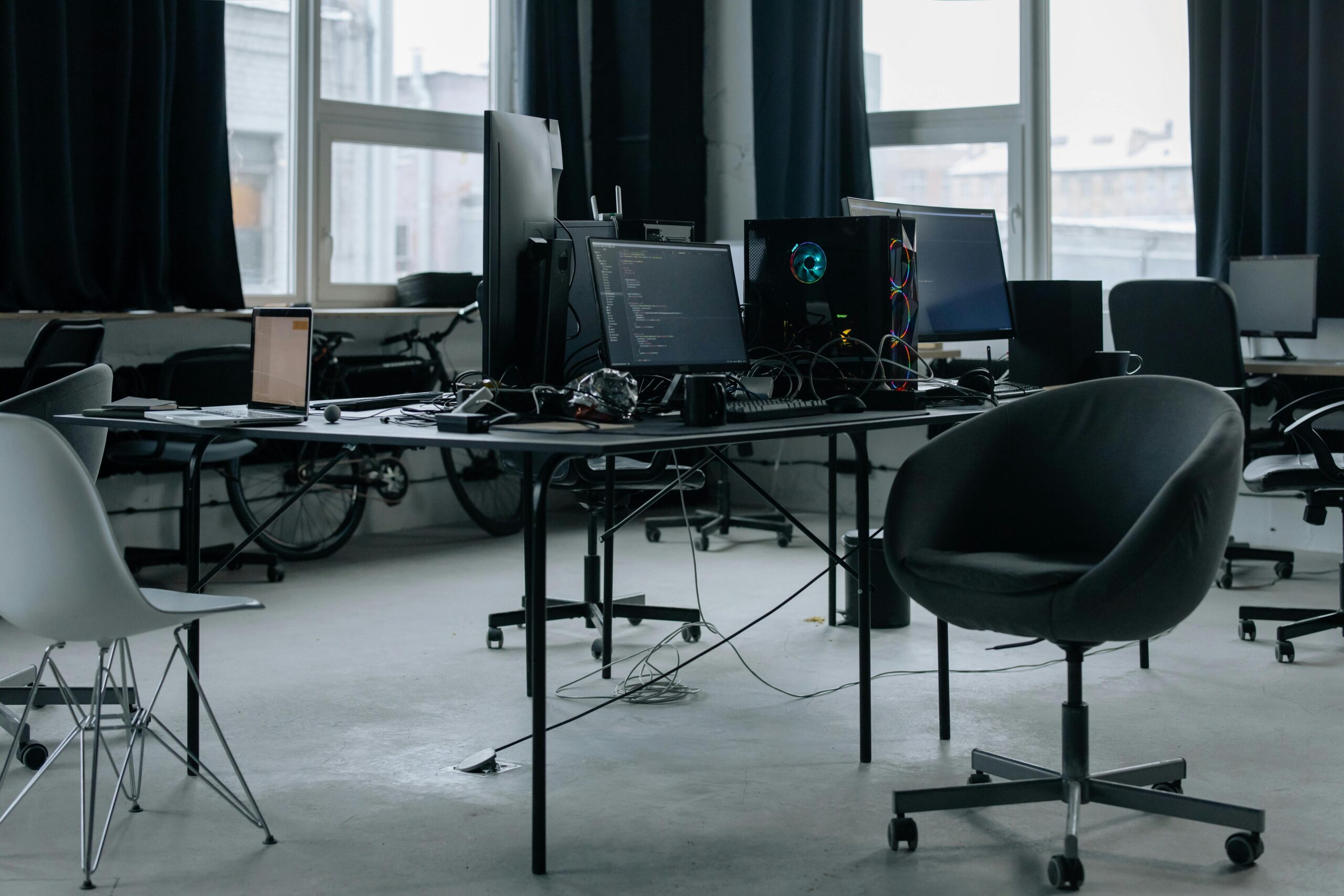 Disorganized desk setup in a dimly lit room, showcasing the tools and gadgets of a technology-focused professional.