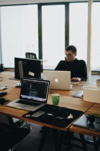 Coding and programming: The laptop screen displays code, suggesting that the person in the image is engaged in software development or programming tasks, highlighting the technological nature of their work.