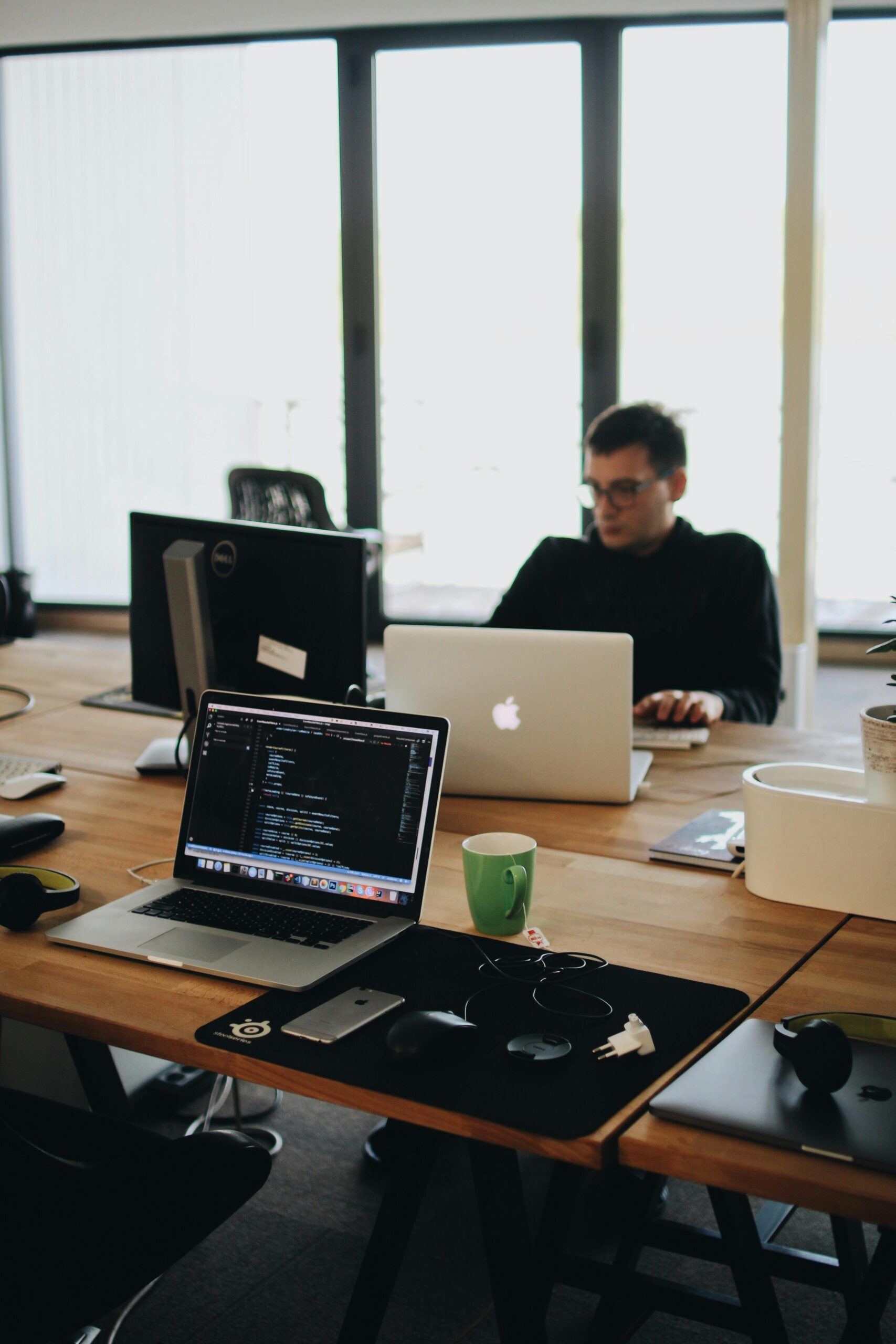 Coding and programming: The laptop screen displays code, suggesting that the person in the image is engaged in software development or programming tasks, highlighting the technological nature of their work.