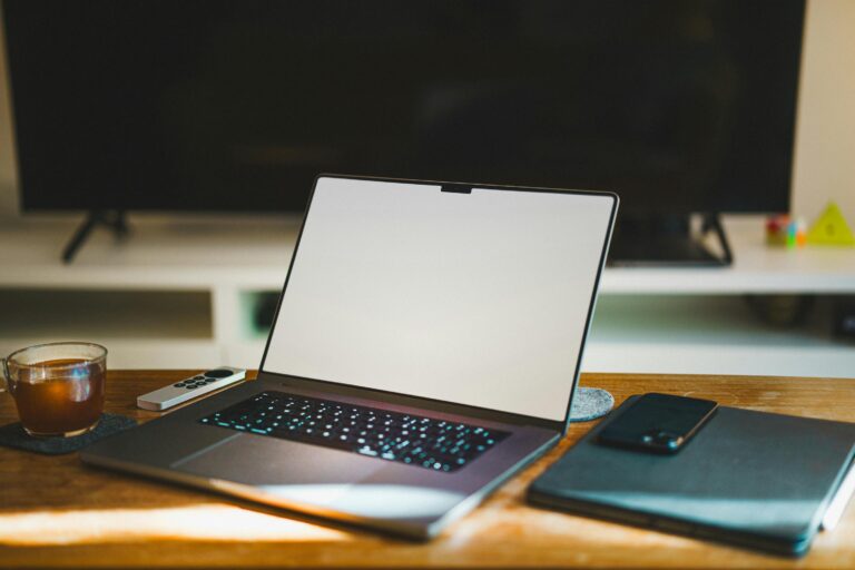 Workspace with laptop, phone, and coffee mug on wooden table.