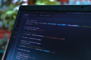 A close-up view of a laptop screen showing a programming code editor with various lines of Python code.