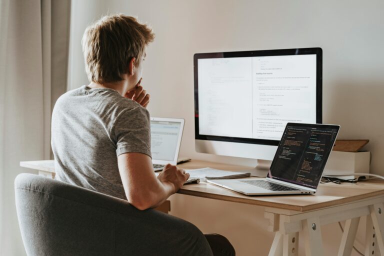 An individual deeply immersed in their digital workspace, surrounded by technology as they tackle software development or other computer-based projects.