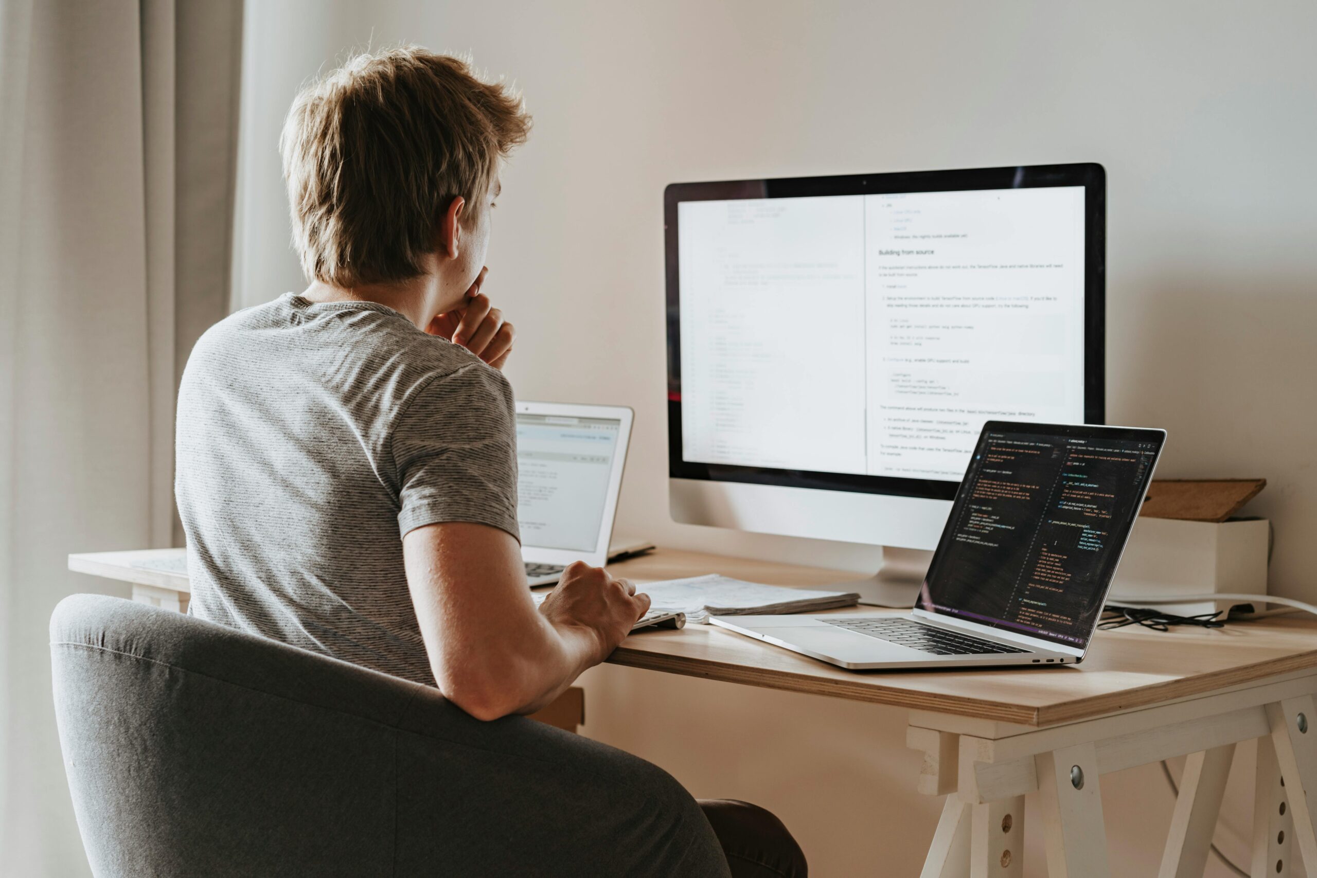 An individual deeply immersed in their digital workspace, surrounded by technology as they tackle software development or other computer-based projects.