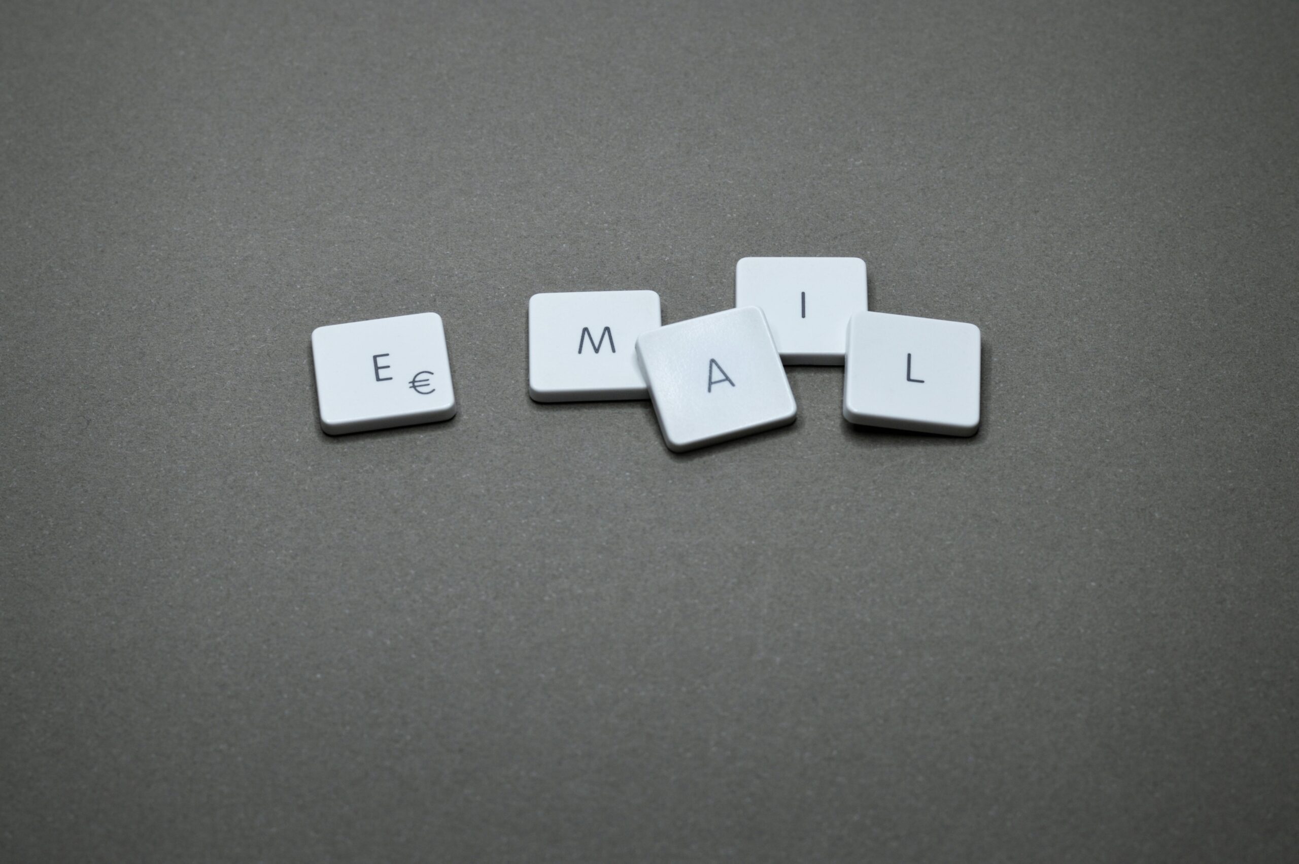 Minimalist image showing individual keyboard keys that spell out the word "Email" against a neutral gray backdrop.